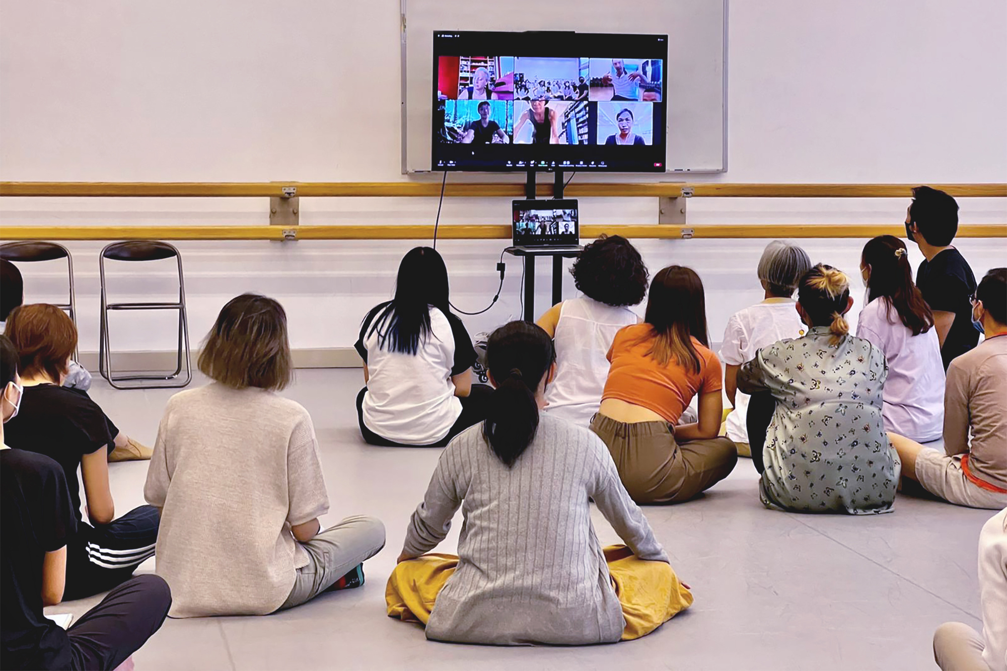 所有藝術家導師在香港演藝學院的舞蹈室參加由我們的意大利培訓團隊提供的線上培訓。 每個人都坐在地板上，注視著放在舞蹈室中間的大電視屏幕，全神貫注地參加培訓。